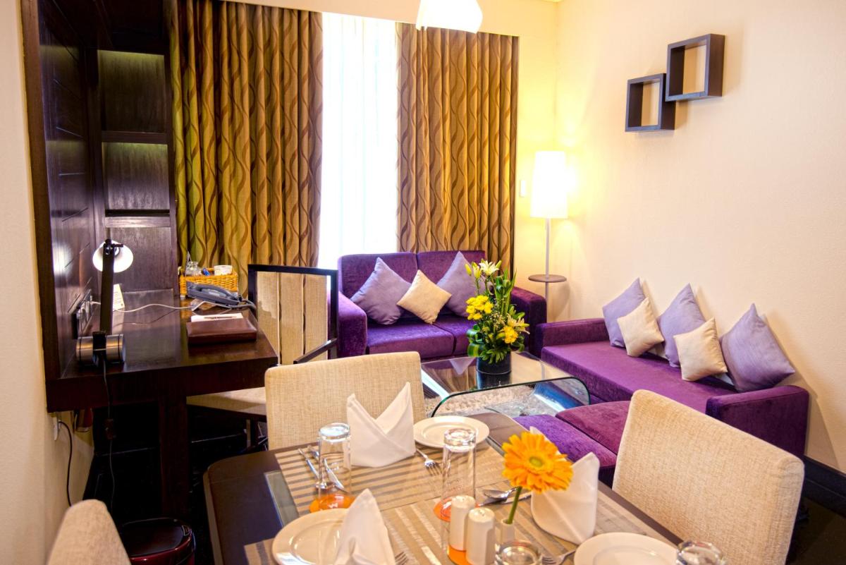 a living room with a table and a purple couch at Sterlings Mac Hotel in Bengaluru