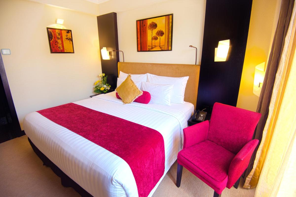 a bedroom with a large bed and a red chair at Sterlings Mac Hotel in Bengaluru
