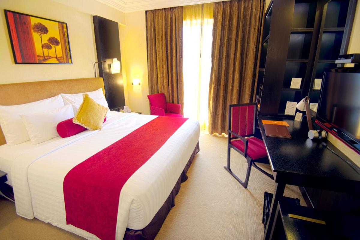 a hotel room with a bed and a television at Sterlings Mac Hotel in Bengaluru