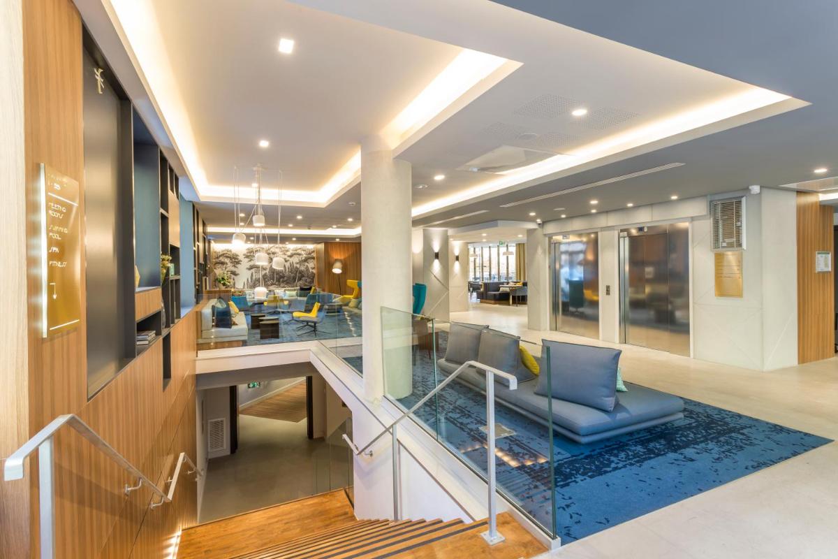 un hall avec un escalier et des chaises bleues dans l'établissement Nemea Appart Hotel Cannes Palais, à Cannes 111 autres photos
