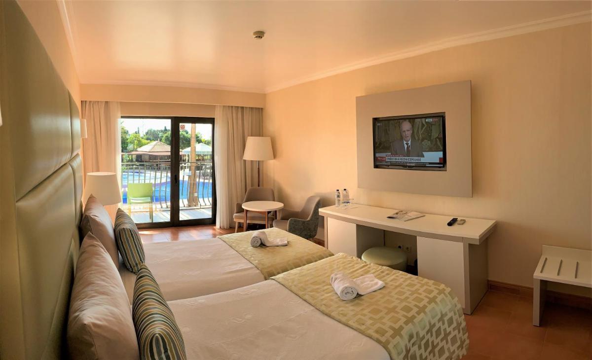 um quarto de hotel com uma cama e uma escrivaninha em Hotel Baia Grande em Albufeira