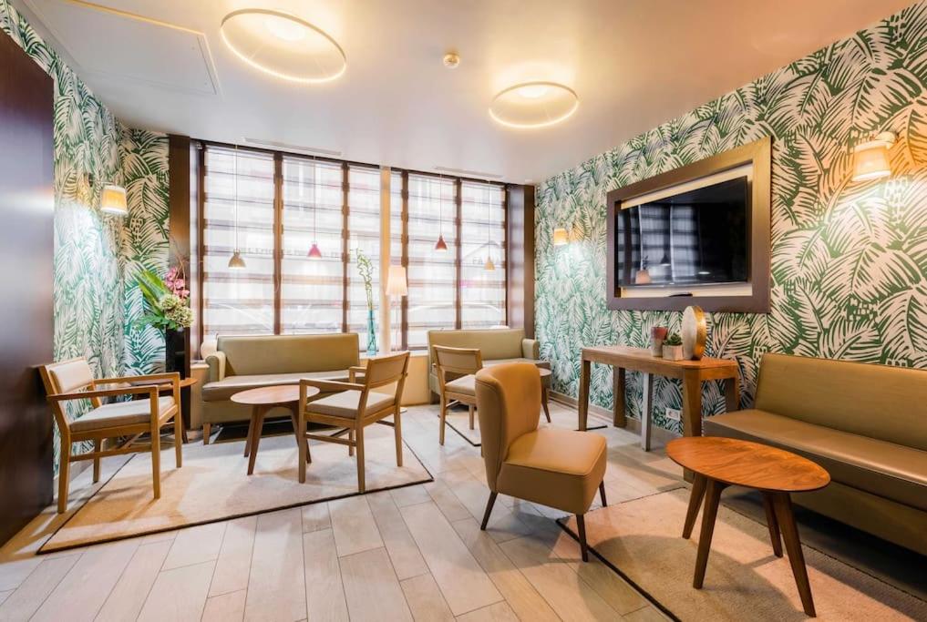 - une salle d'attente avec des tables, des chaises et un canapé dans l'établissement Hotel Eden, à Paris