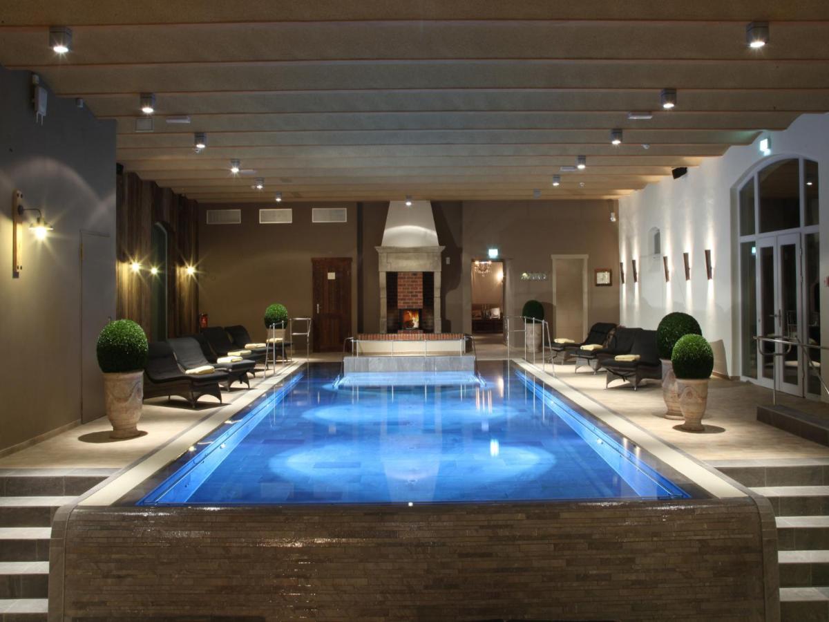 einen Pool in einer Hotellobby mit Stühlen und einem Kamin in der Unterkunft Spa & GolfResort Weimarer Land in Blankenhain