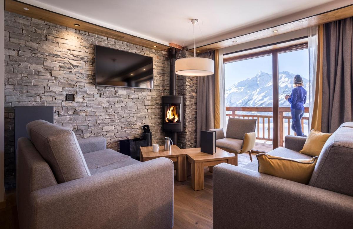 un salon avec des canapés et un mur en pierre dans l'établissement Hôtel Alparena & Spa - 4 étoiles, à La Rosière