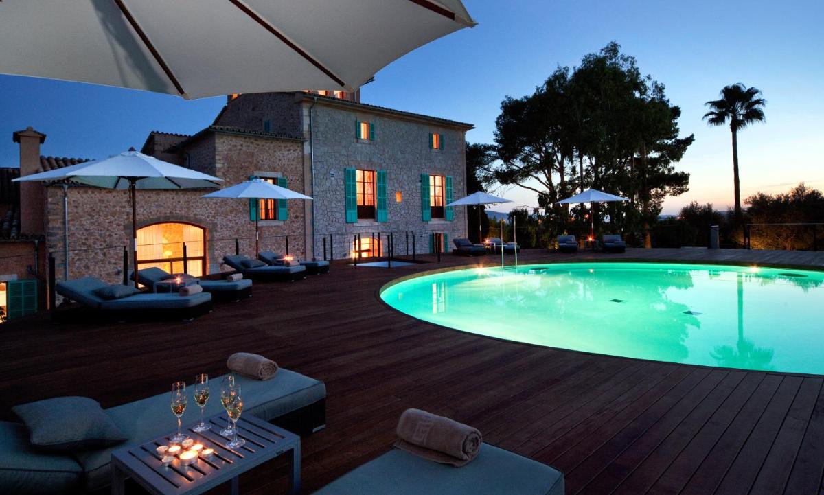 Una piscina con sofás y sombrillas al lado de un edificio. en Sa Cabana Hotel & Spa - Adults Only, en Consell