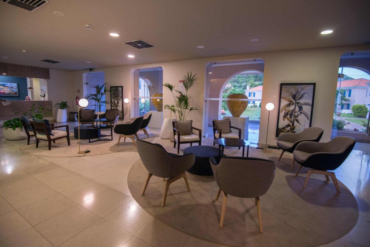 uma sala de espera com cadeiras, mesas e janelas em Azoris Faial Garden – Resort Hotel em Horta
