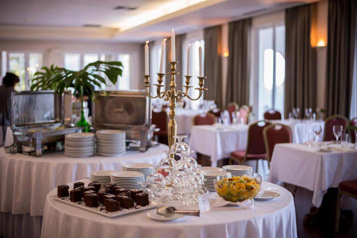 uma sala de jantar com mesas e toalhas de mesa brancas em Azoris Faial Garden – Resort Hotel em Horta