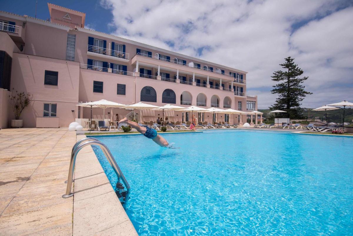 uma pessoa a mergulhar numa piscina ao lado de um hotel em Azoris Faial Garden – Resort Hotel em Horta