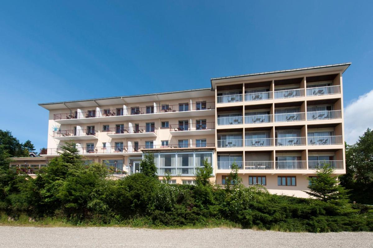 un immeuble d'appartements avec des arbres devant dans l'établissement Alexain Hotel Restaurant & Wellness - Colmar Ouest, à Trois-Épis