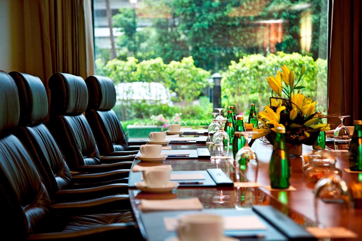 a long table with chairs and a table with flowers on it at Radisson Blu Plaza Delhi Airport in New Delhi a long table with chairs and a table with flowers on it at Radisson Blu Plaza Delhi Airport in New Delhi