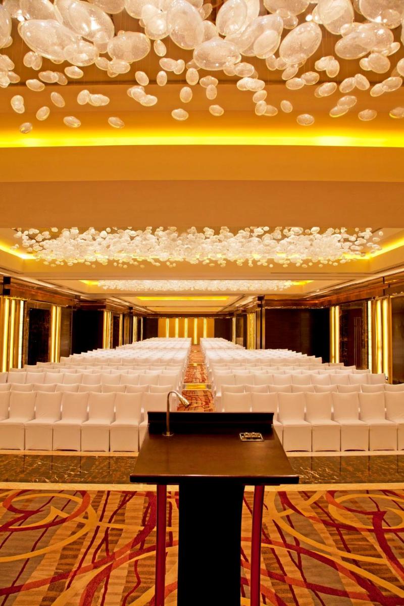 a large banquet hall with white seats in a room at Radisson Blu Plaza Delhi Airport in New Delhi a large banquet hall with white seats in a room at Radisson Blu Plaza Delhi Airport in New Delhi