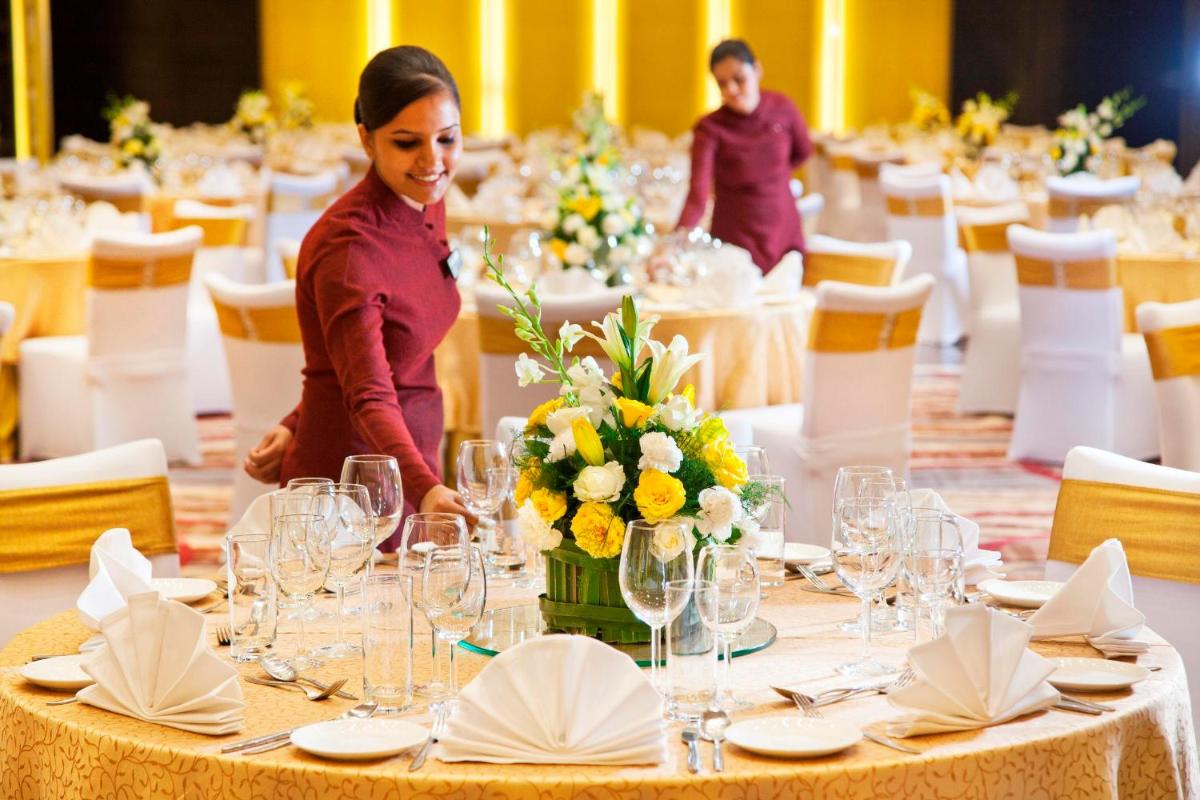 a woman standing at a table in a banquet hall at Radisson Blu Plaza Delhi Airport in New Delhi a woman standing at a table in a banquet hall at Radisson Blu Plaza Delhi Airport in New Delhi