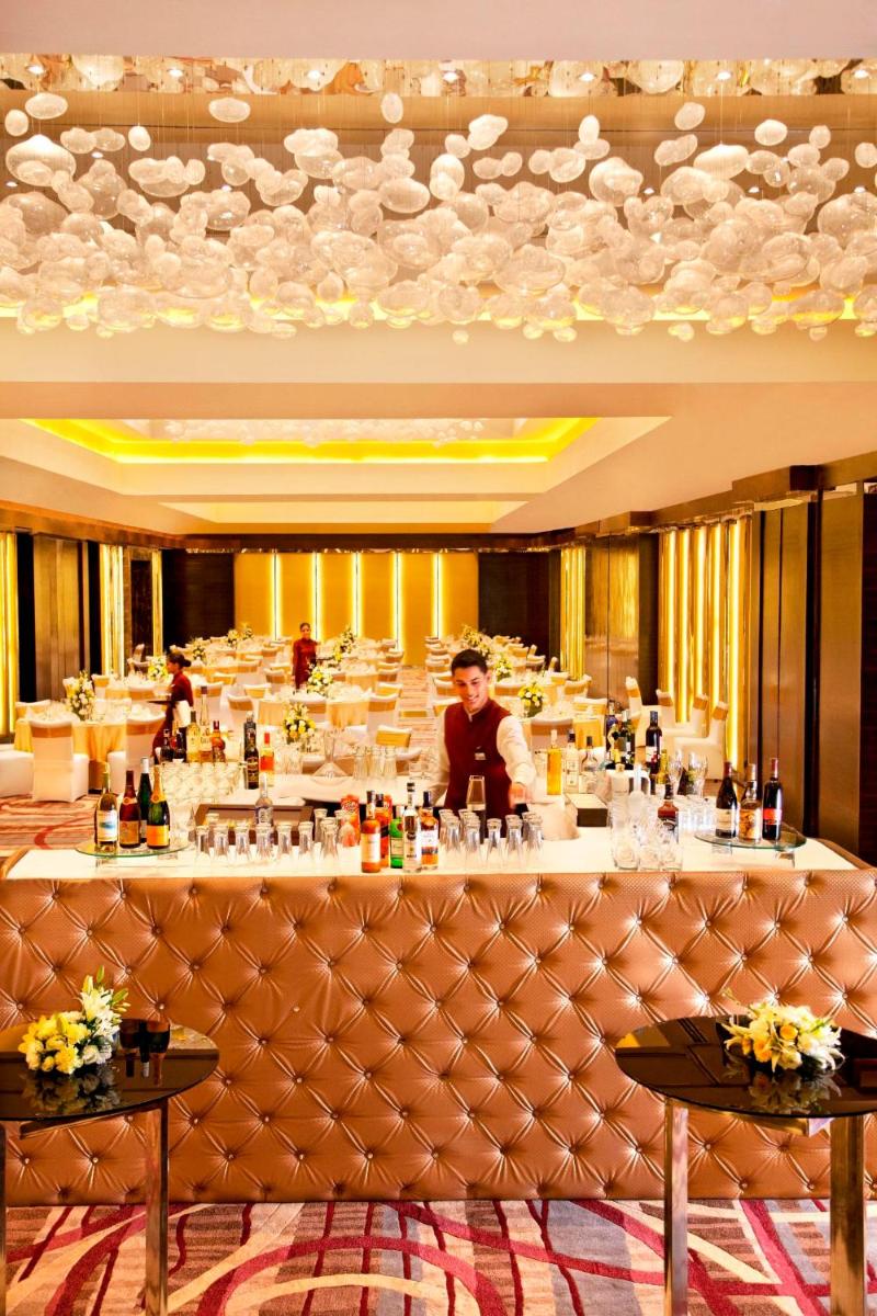a man standing behind a bar in a restaurant at Radisson Blu Plaza Delhi Airport in New Delhi a man standing behind a bar in a restaurant at Radisson Blu Plaza Delhi Airport in New Delhi