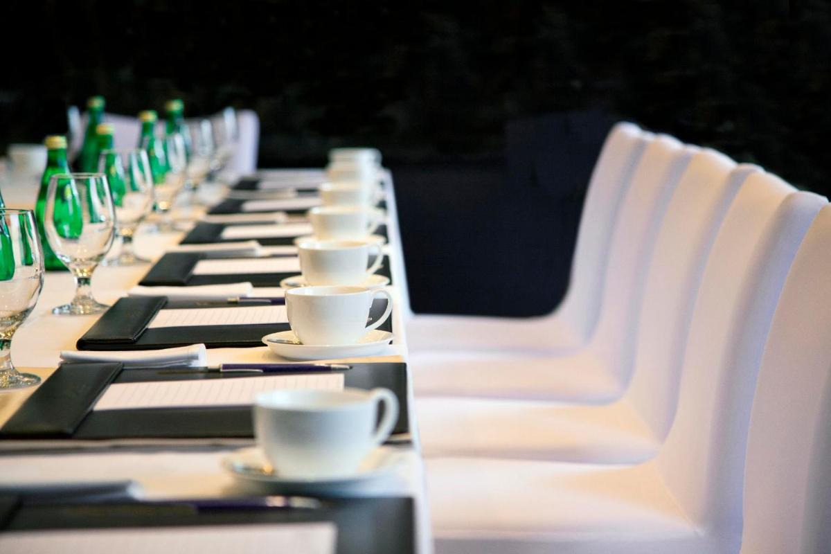 a long table with white chairs and coffee cups at Radisson Blu Plaza Delhi Airport in New Delhi a long table with white chairs and coffee cups at Radisson Blu Plaza Delhi Airport in New Delhi