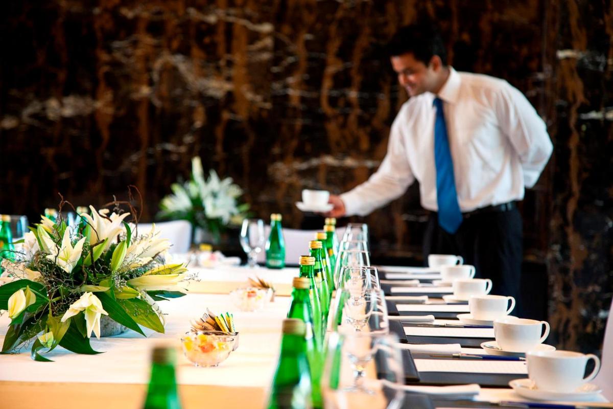 a man in a tie standing in front of a table at Radisson Blu Plaza Delhi Airport in New Delhi a man in a tie standing in front of a table at Radisson Blu Plaza Delhi Airport in New Delhi