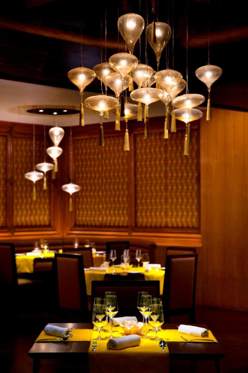 a dining room with yellow tables and a chandelier at Radisson Blu Plaza Delhi Airport in New Delhi a dining room with yellow tables and a chandelier at Radisson Blu Plaza Delhi Airport in New Delhi