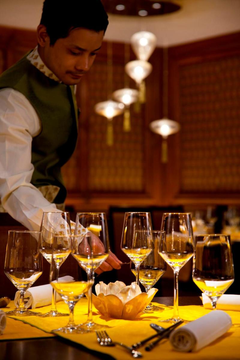a man standing in front of a table with wine glasses at Radisson Blu Plaza Delhi Airport in New Delhi a man standing in front of a table with wine glasses at Radisson Blu Plaza Delhi Airport in New Delhi