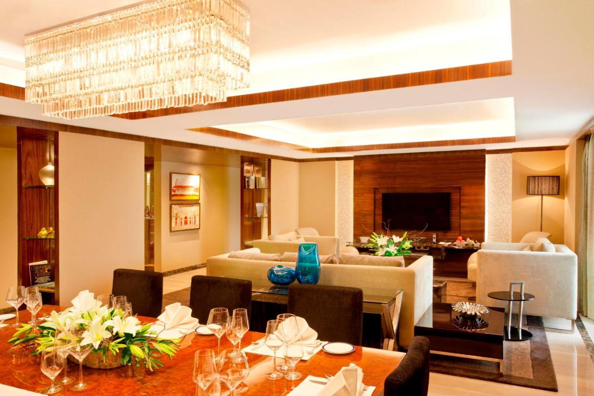a dining room and living room with a chandelier at Radisson Blu Plaza Delhi Airport in New Delhi a dining room and living room with a chandelier at Radisson Blu Plaza Delhi Airport in New Delhi
