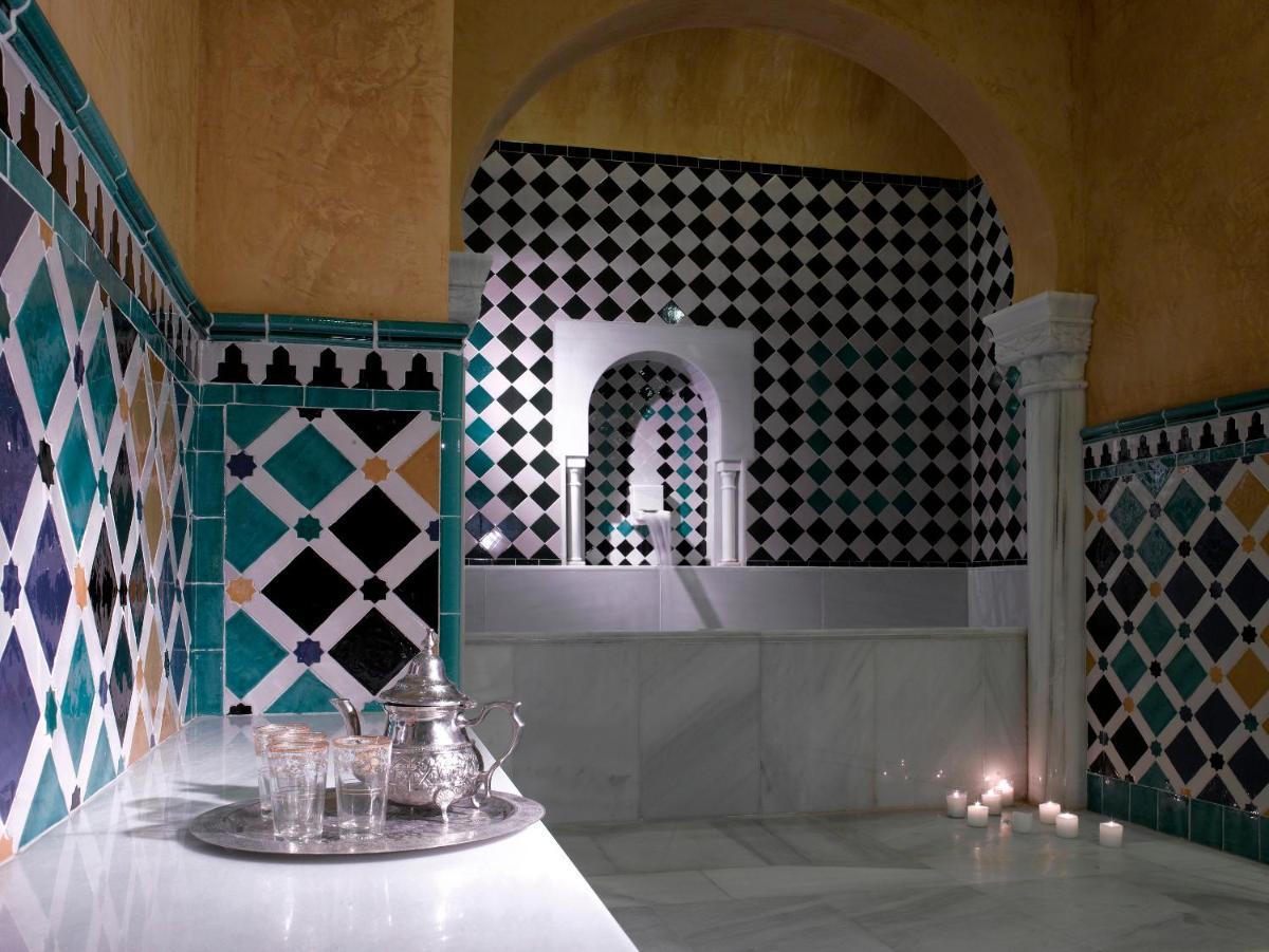 Habitación con una mesa con velas y una pared de azulejos. en Hotel Macià Real De La Alhambra, en Granada