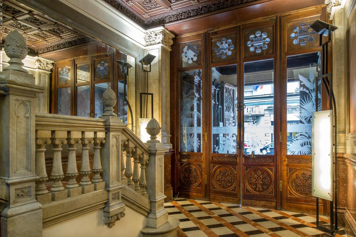 un vestíbulo con una escalera y una gran puerta de madera en Catalonia Plaza Catalunya, en Barcelona