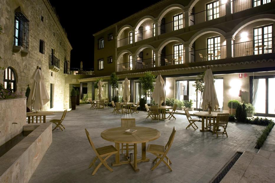 Un patio con mesas y sillas en un edificio. en Hotel Palacio de Mengibar, en Mengíbar