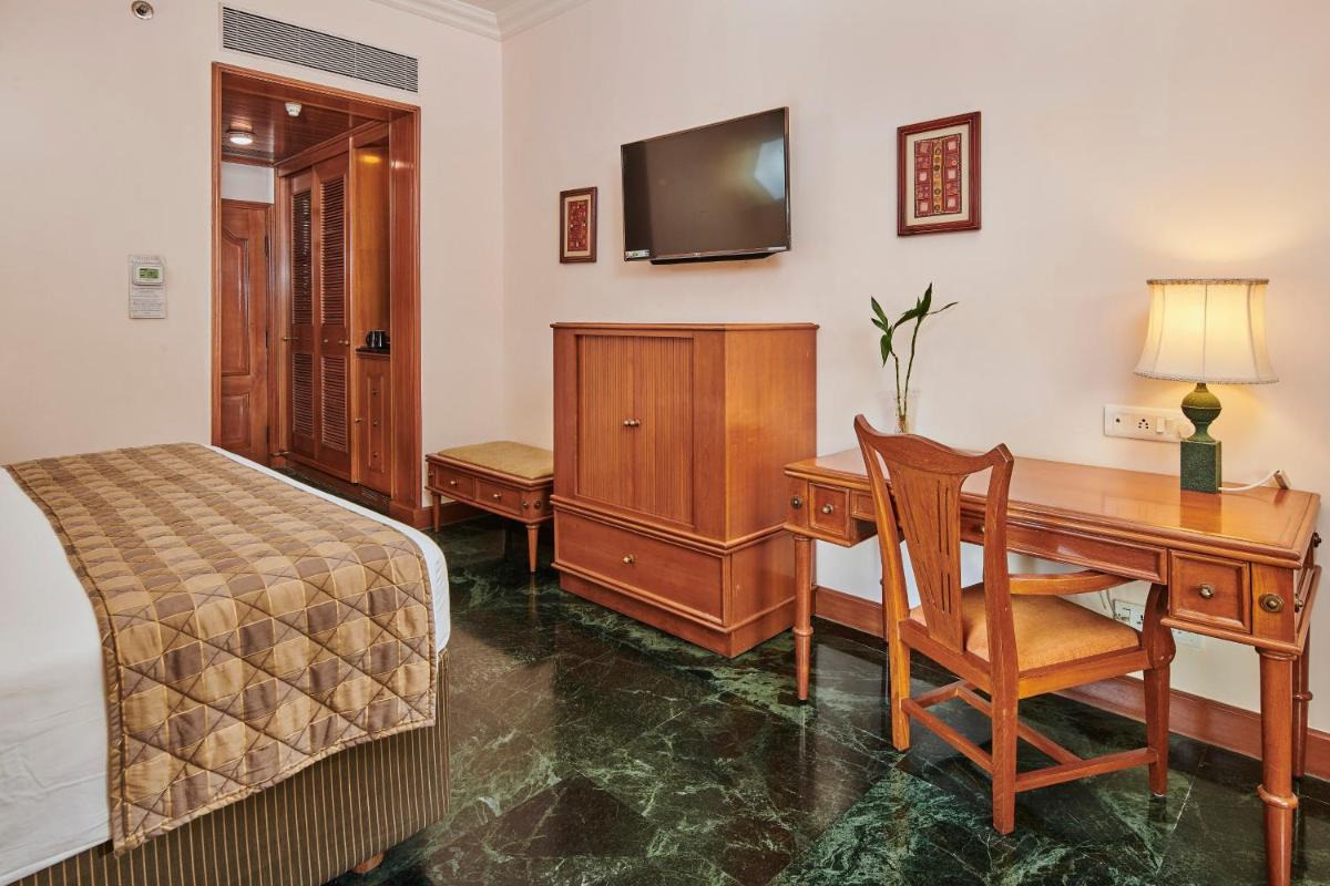 a bedroom with a desk and a bed and a desk and a television at The Ummed Ahmedabad Airport in Ahmedabad