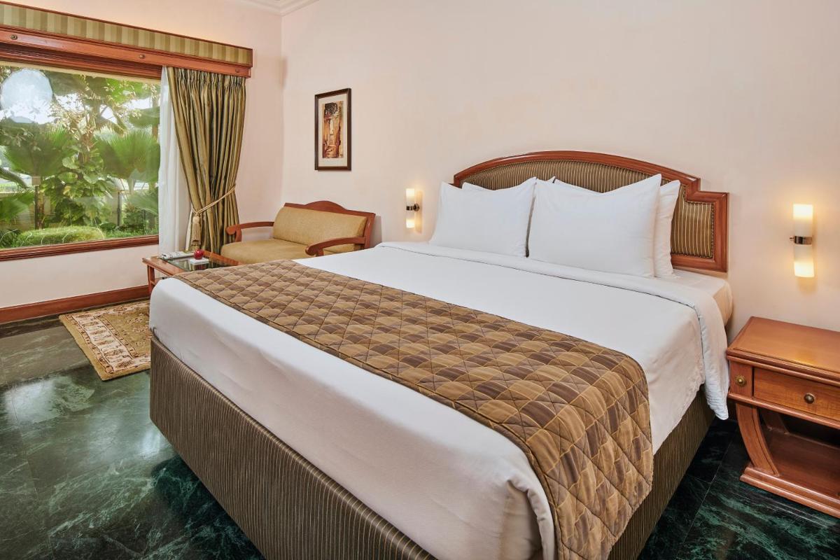 a hotel room with a large bed and a window at The Ummed Ahmedabad Airport in Ahmedabad