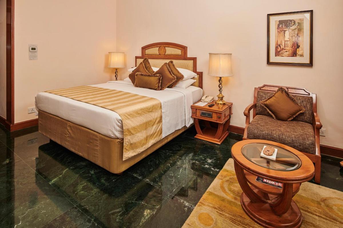 a hotel room with a bed and a chair at The Ummed Ahmedabad Airport in Ahmedabad