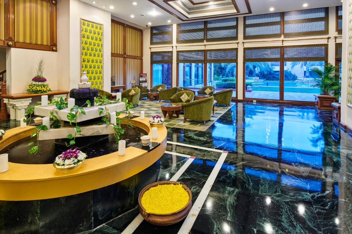 a hotel lobby with a pool in the middle at The Ummed Ahmedabad Airport in Ahmedabad