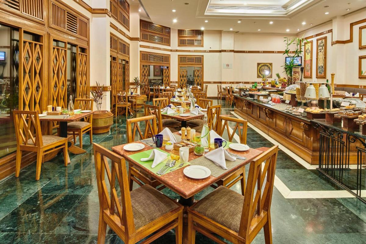 a restaurant with tables and chairs in a room at The Ummed Ahmedabad Airport in Ahmedabad