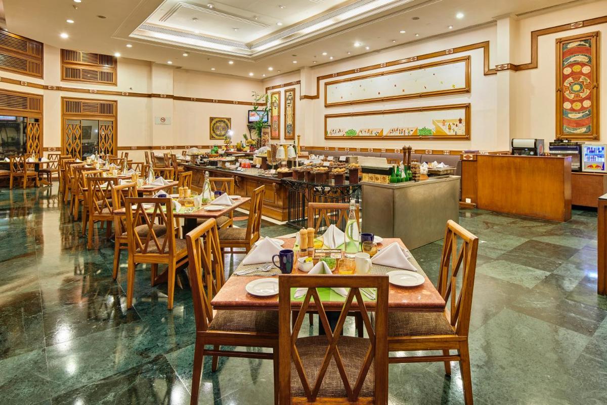 a restaurant with wooden tables and chairs and a buffet at The Ummed Ahmedabad Airport in Ahmedabad