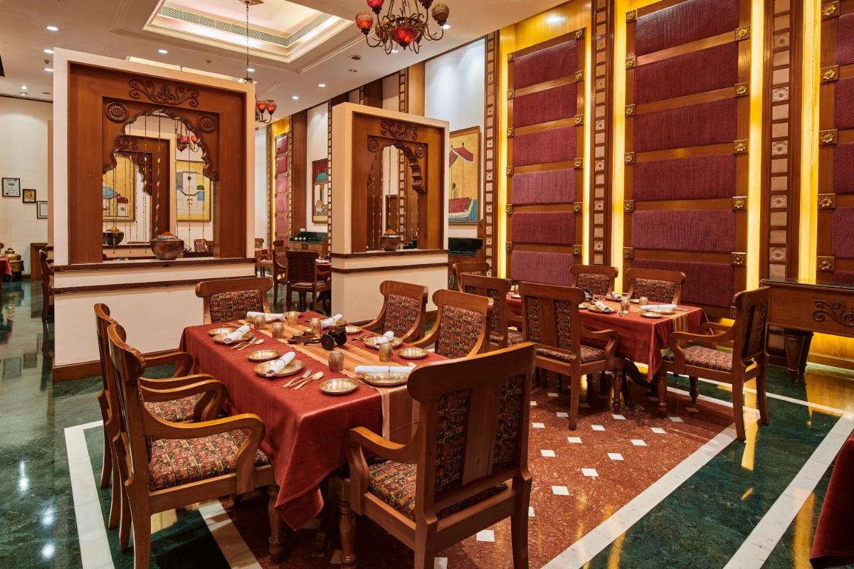 a restaurant with tables and chairs in a room at The Ummed Ahmedabad Airport in Ahmedabad