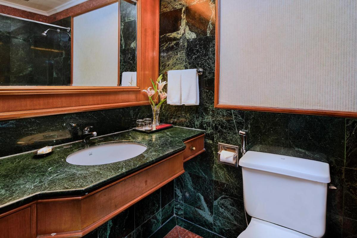 a bathroom with a sink and a toilet and a mirror at The Ummed Ahmedabad Airport in Ahmedabad