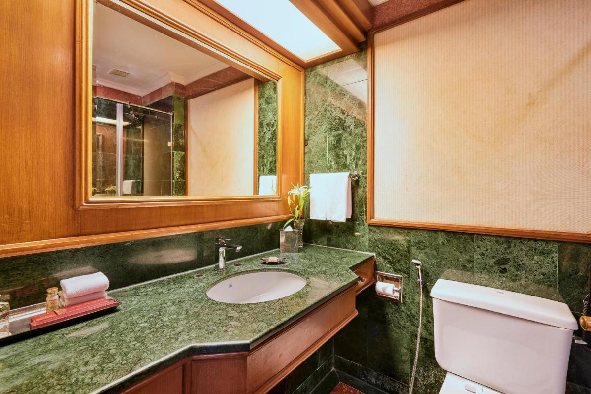 a bathroom with a sink and a mirror and a toilet at The Ummed Ahmedabad Airport in Ahmedabad
