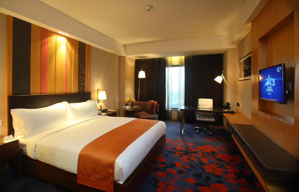 a hotel room with a bed and a desk and a television at Holiday Inn New Delhi Mayur Vihar Noida by IHG in New Delhi a hotel room with a bed and a desk and a television at Holiday Inn New Delhi Mayur Vihar Noida by IHG in New Delhi