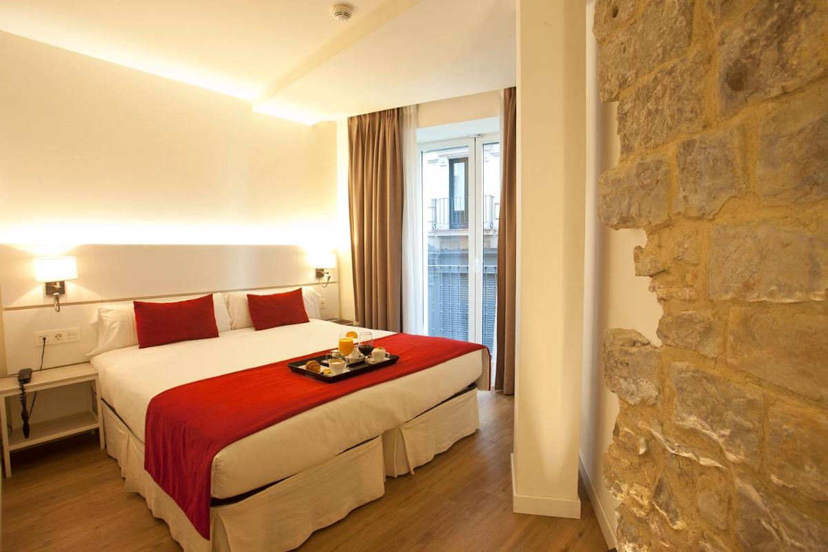Una habitación de hotel con una cama y una pared de piedra. en Hotel Pompaelo Plaza del Ayuntamiento & Spa, en Pamplona