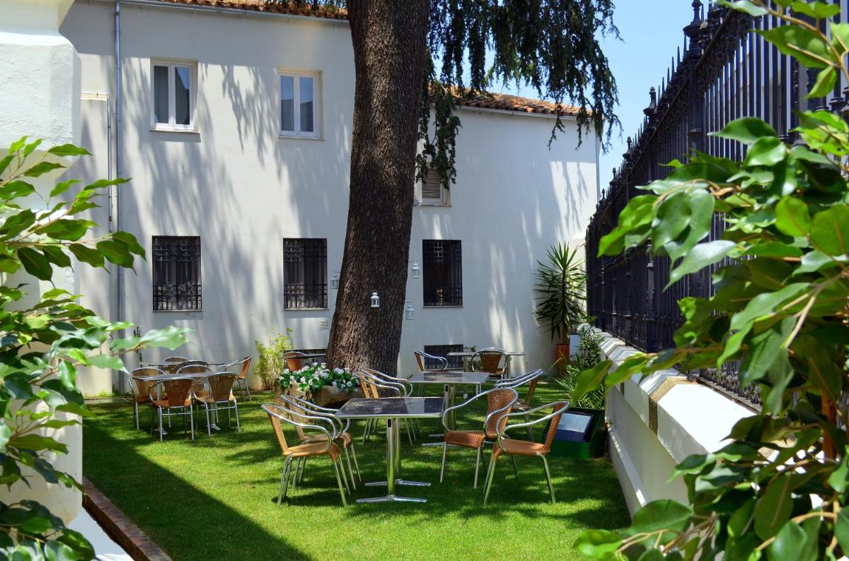 un patio con sillas, una mesa y un árbol en Hotel Mirador de Llerena, en Llerena