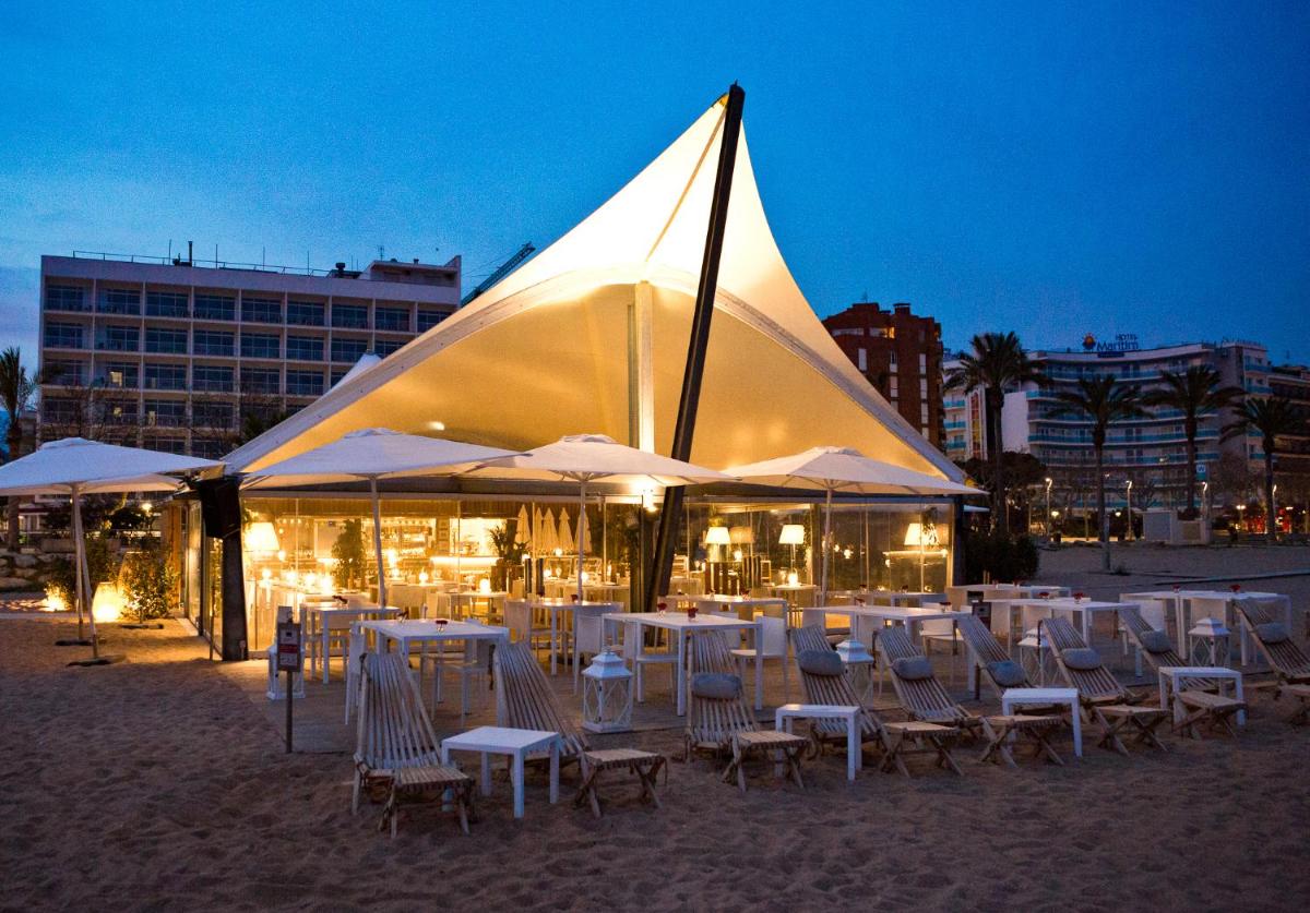Un grupo de sillas y sombrillas en la playa por la noche. en Hotel Bernat II 4*Sup, en Calella