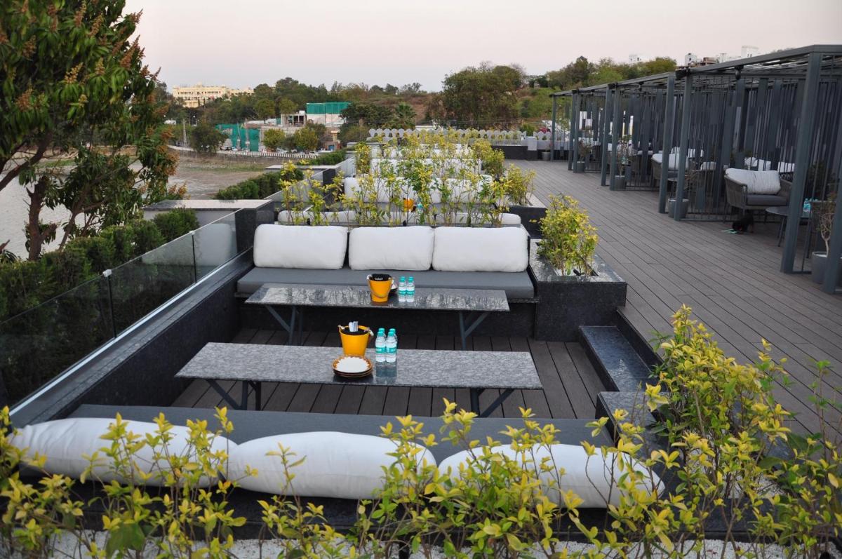 a patio with couches and tables on a roof at Hotel Lakend in Udaipur