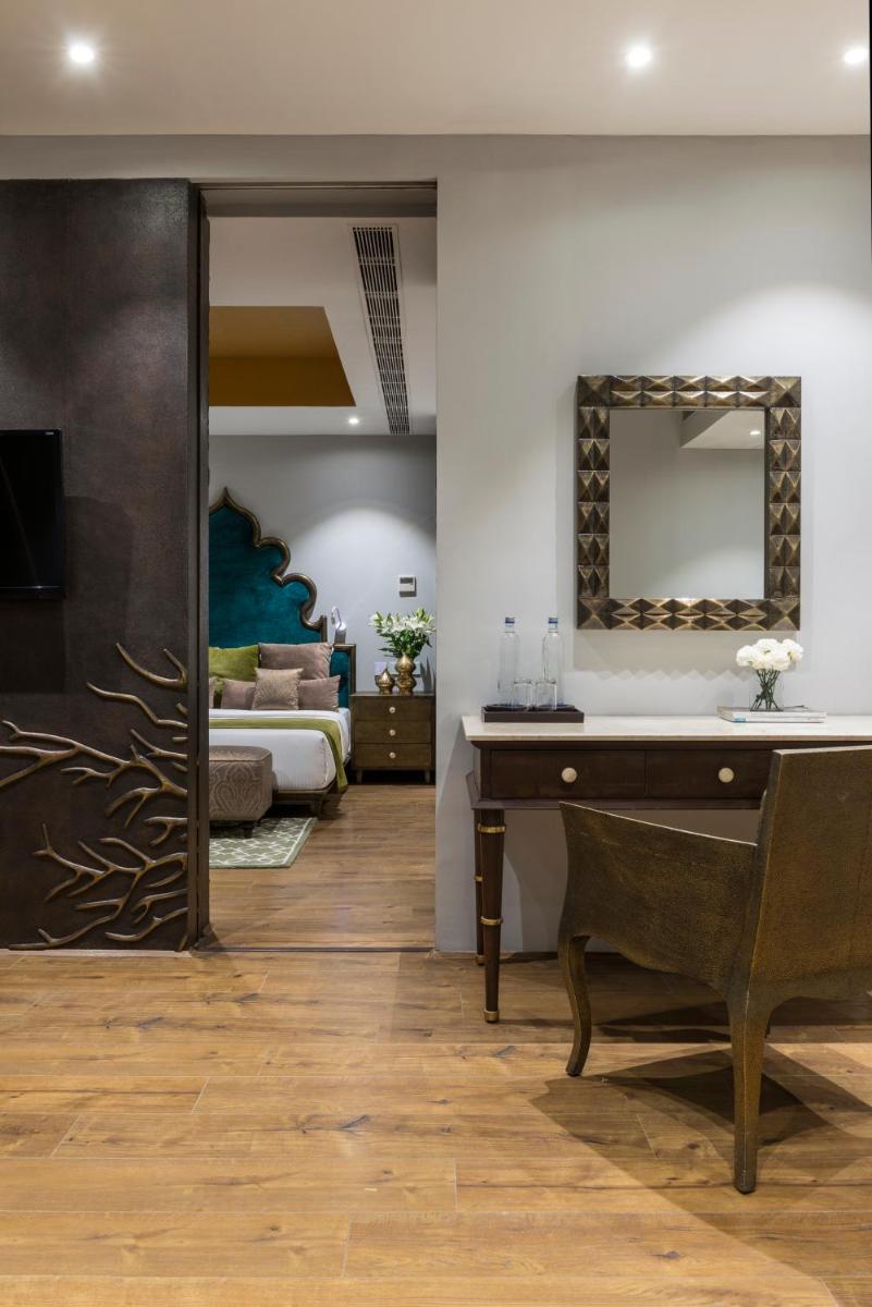 a bedroom with a bed and a desk and a mirror at Hotel Lakend in Udaipur