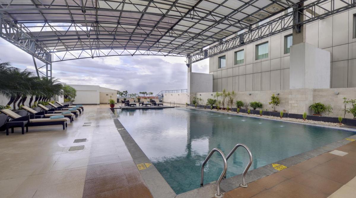 a large swimming pool in a building with chairs at Pride Plaza Hotel, Kolkata in Kolkata