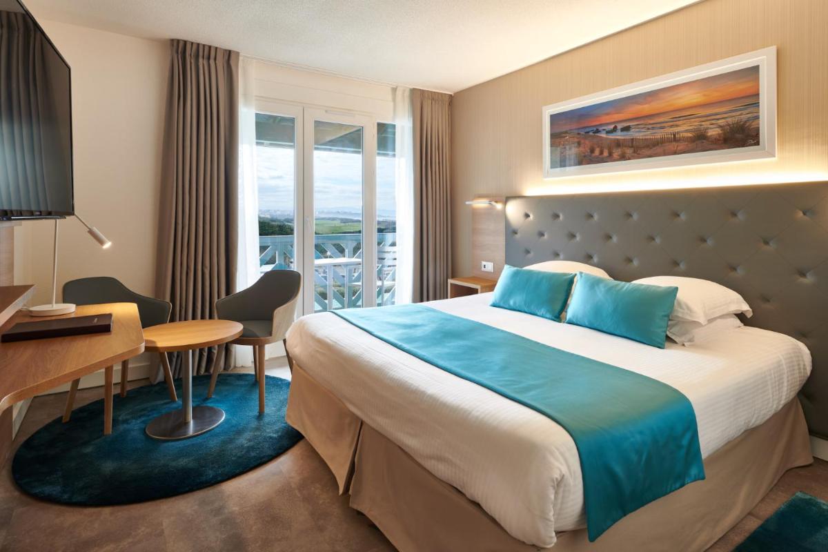 une chambre d'hôtel avec un lit, un bureau et une fenêtre dans l'établissement Atlanthal, à Anglet