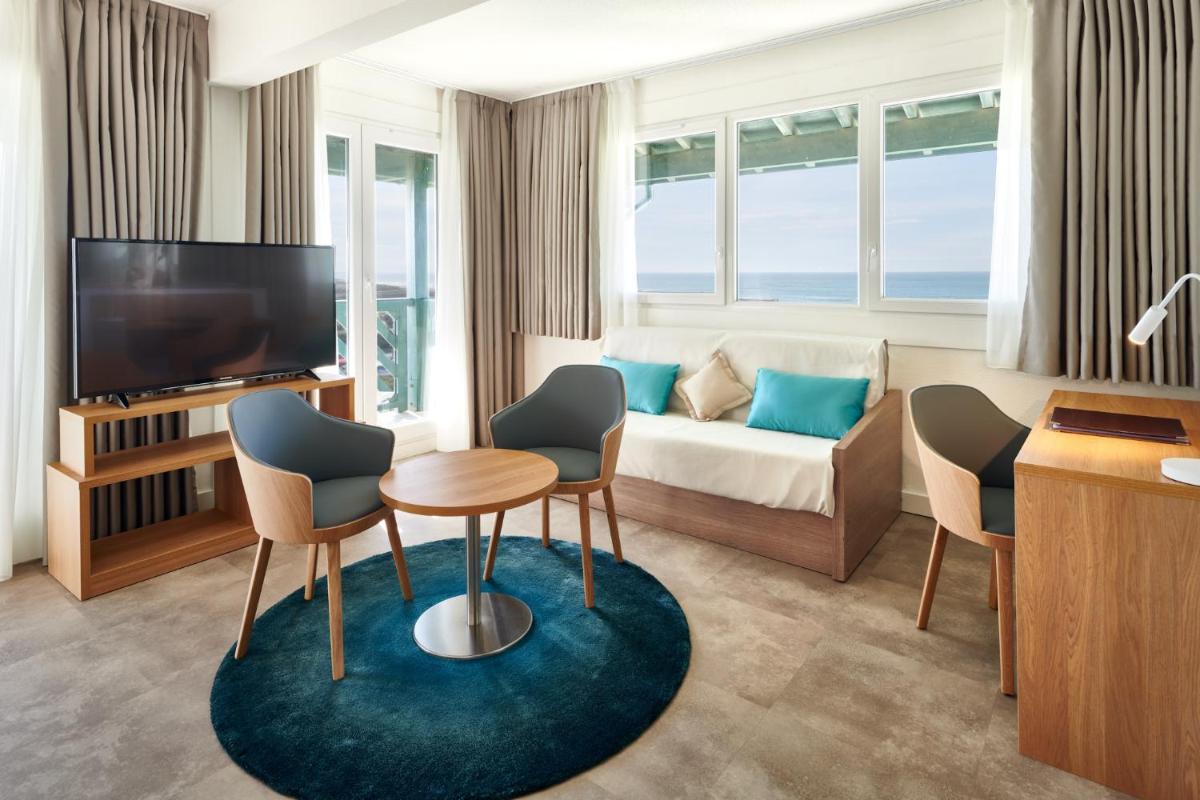une chambre d'hôtel avec un canapé, une table et des chaises dans l'établissement Atlanthal, à Anglet