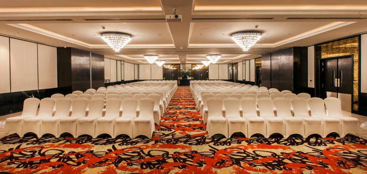 a row of white chairs in a room with an orange carpet at Lemon Tree Premier City Center Pune in Pune