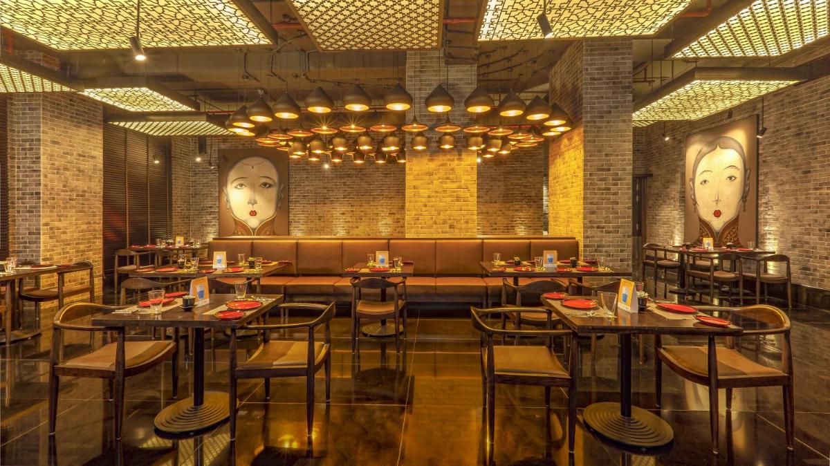 a restaurant with tables and chairs and faces on the walls at Lemon Tree Premier City Center Pune in Pune