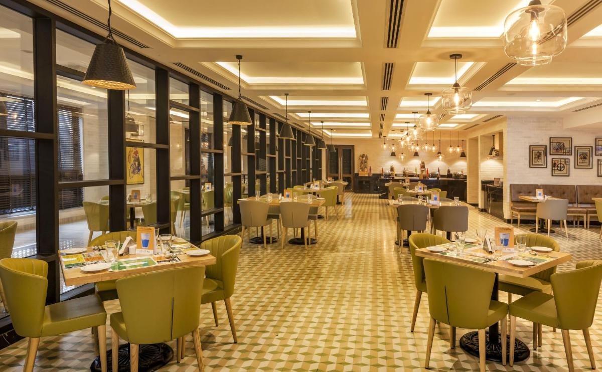 a restaurant with tables and chairs in a room at Lemon Tree Premier City Center Pune in Pune