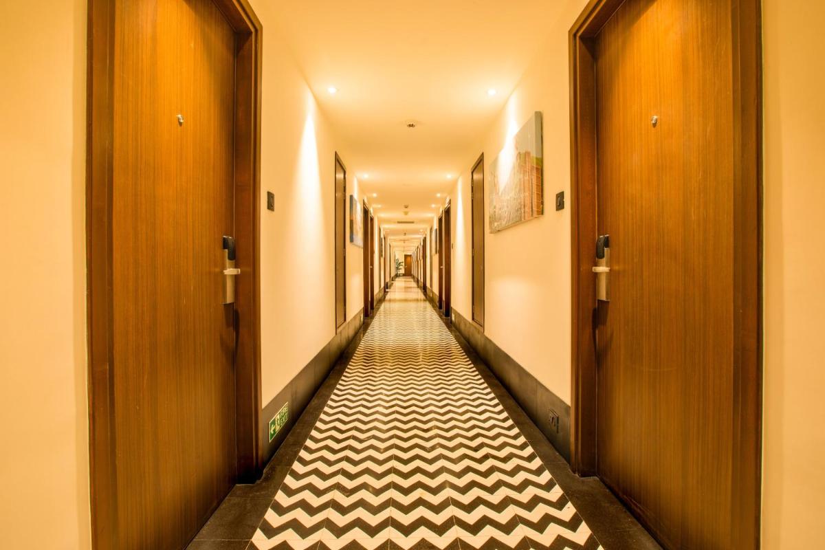 a hallway with a long corridor with white and black tiles at Lemon Tree Premier City Center Pune in Pune