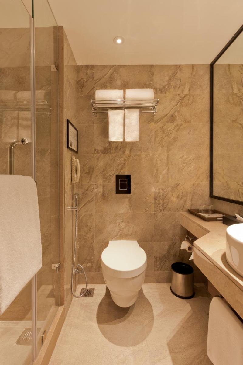 a bathroom with a toilet and a shower and a sink at Lemon Tree Premier City Center Pune in Pune