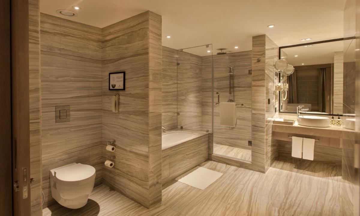 a bathroom with a tub and a toilet and a sink at Lemon Tree Premier City Center Pune in Pune