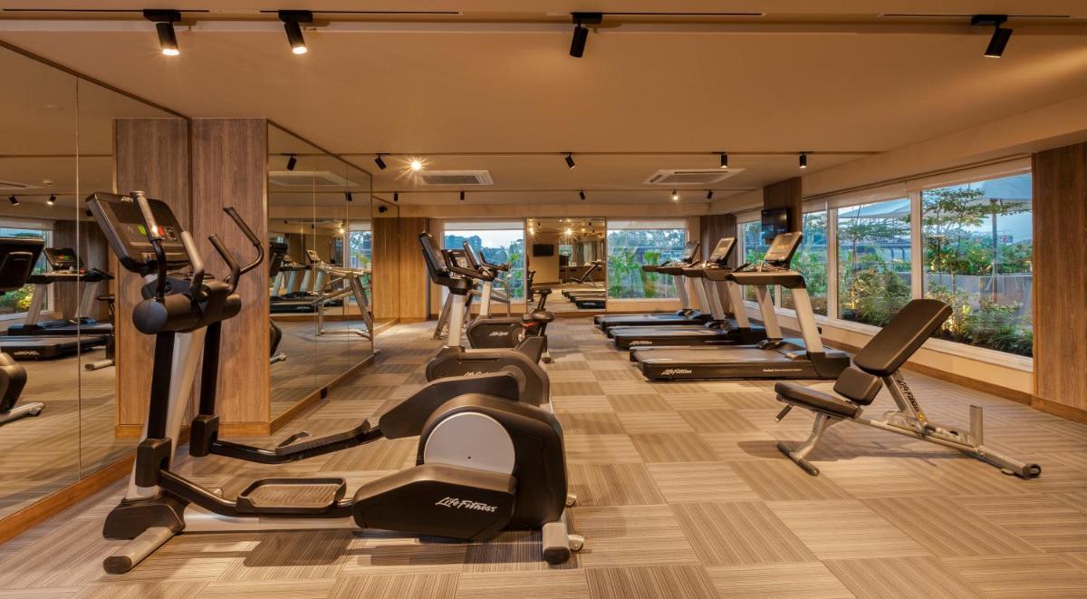 a gym with a row of treadmills and ellipticals at Lemon Tree Premier City Center Pune in Pune